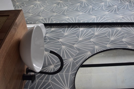 Baño con lavamanos blanco y baldosas de cemento en abanico