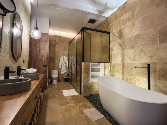 Baño en travertino con bañera exenta y doble lavamanos