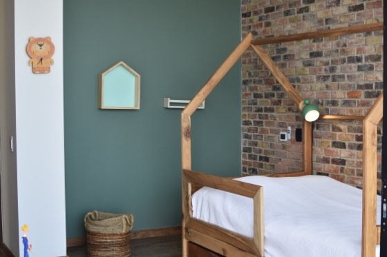 Habitación infantil con cama cabaña de madera y muro de ladrillo