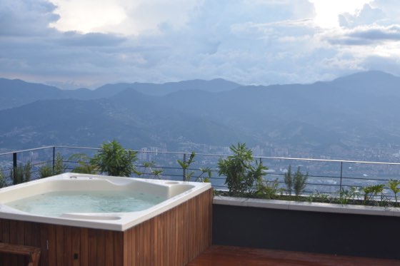 Jacuzzi en deck de madera al crepúsculo con montañas azuladas