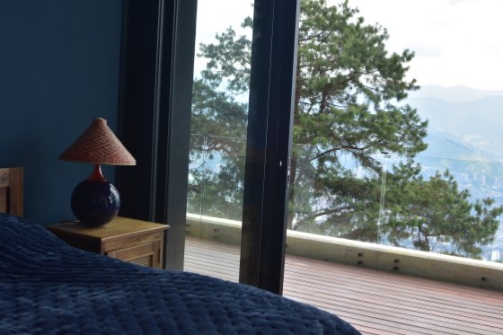 Suite azul abierta a terraza con pinos y vista a la ciudad
