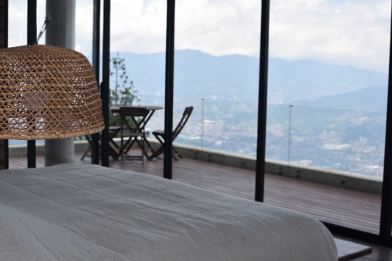 Cama blanca frente a terraza con panorama del valle