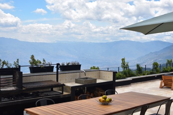 Terraza con parrilla argentina, mesa de madera y vista al valle
