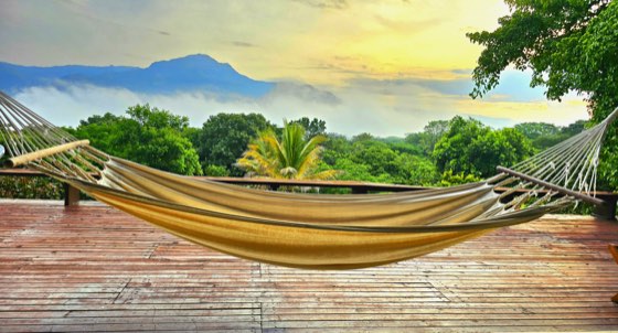 Hamaca en deck de madera al amanecer frente a las montañas