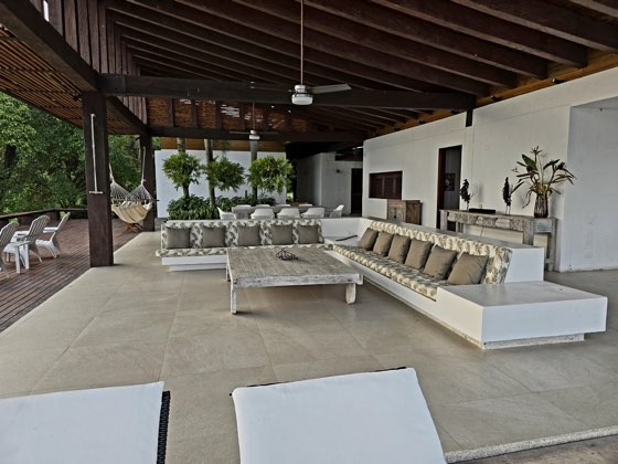 Salón exterior cubierto con sofás y hamaca