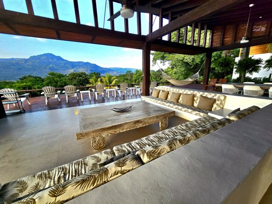 Salón exterior con techo de madera y vista a las montañas
