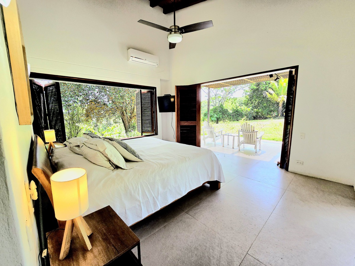 Habitación con cama king abierta a terraza privada y jardín en Villa Las Guacamayas